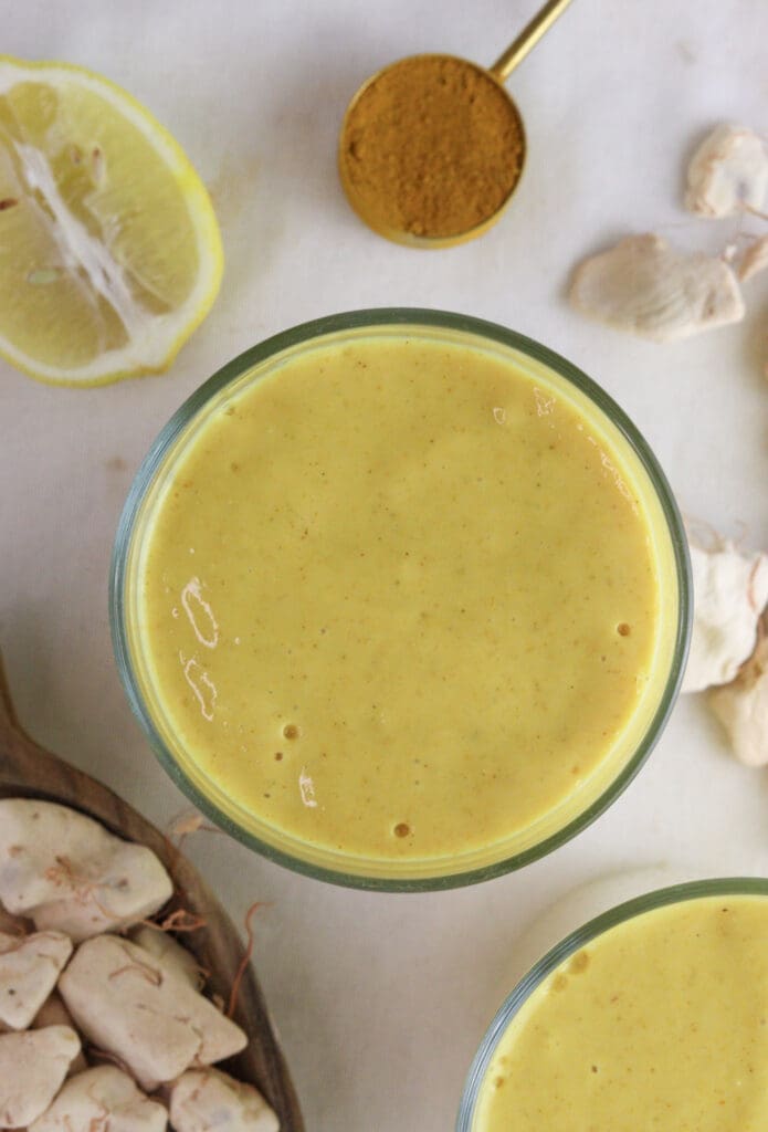 A glass of baobab smoothie with ginger and honey, a healthy drink with turmeric, baobab fruit pulp and lemons in the background